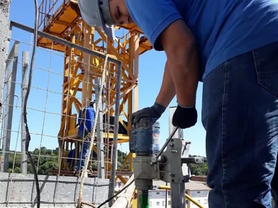 Operador executando furo diamantado em laje durante obra predial na Grande São Paulo