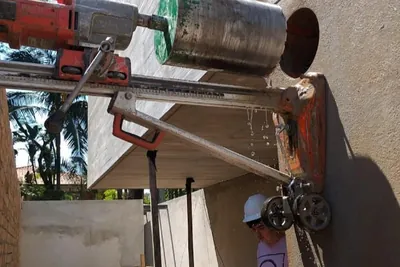 Perfuratriz diamantada fixada em viga de concreto durante execução de furo