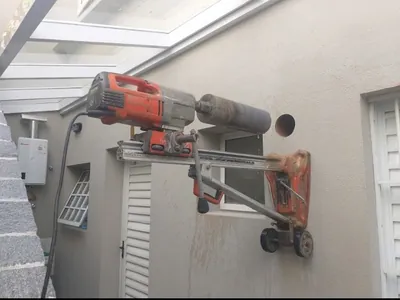 Perfuratriz diamantada ancorada em parede externa de concreto para furo horizontal